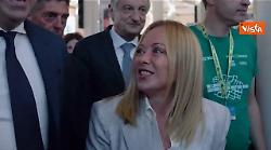 Meloni arriva al Meeting di Rimini accolta dagli applausi. Poi autografa il suo libro a un fan